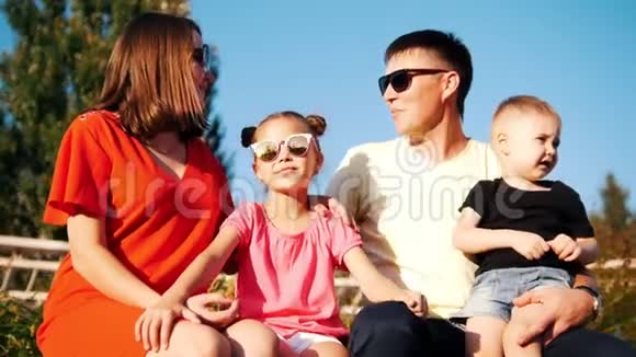 阳光明媚的夏日一家人坐在公园里戴着太阳镜视频的预览图