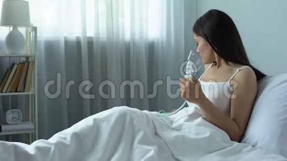 患病妇女在床上通过雾化吸入药物呼吸道疾病视频的预览图