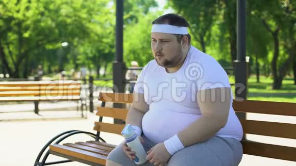公园里紧张的健身活动后胖子呼吸急促喝水视频的预览图