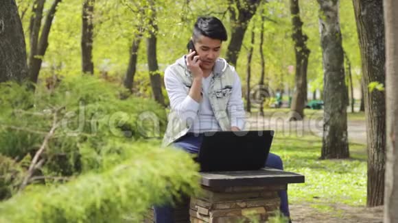 有笔记本电脑的亚洲人在公园打电话视频的预览图