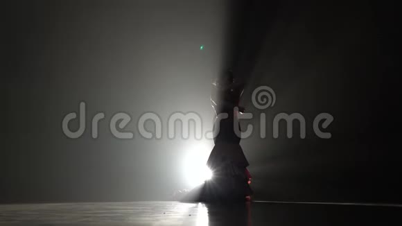 女孩用她的身体跳平稳的动作从后面的光烟雾背景慢动作剪影视频的预览图