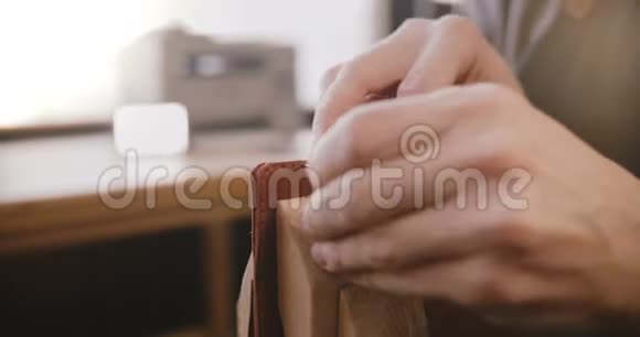男手缝制手工皮革制品的特写镜头在同工制造车间用针头在马鞍上缝制视频的预览图