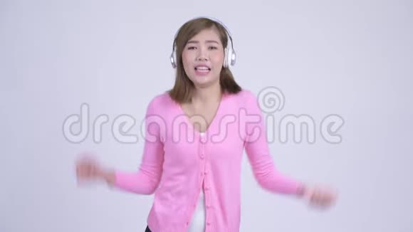 年轻快乐的亚洲女人听音乐跳舞视频的预览图