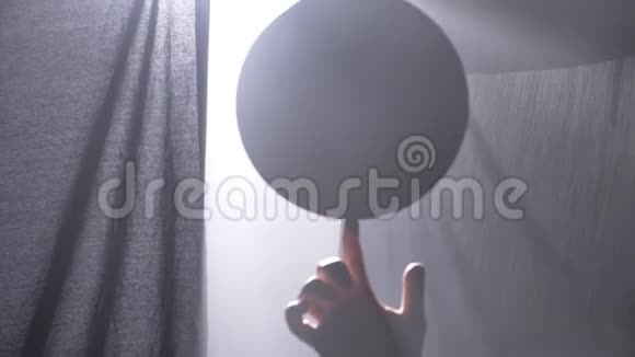 篮球运动员在漆黑的雾蒙蒙的房间里用一根手指旋转球视频的预览图