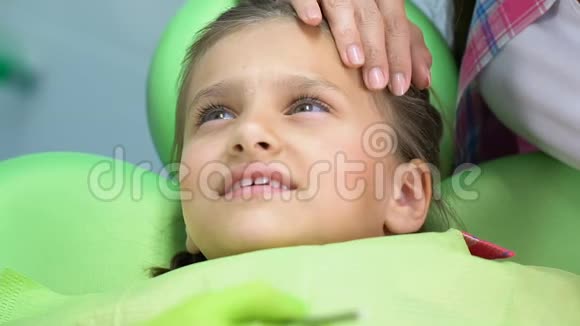 妈妈在检查牙齿时安慰吓坏了的小女孩孩子们的恐惧视频的预览图