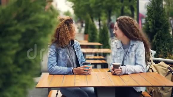 快乐的年轻女性最好的朋友在户外咖啡馆和喝咖啡的时候在餐桌上谈笑风生视频的预览图
