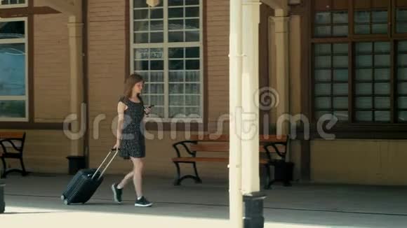 带套装的女人正在用智能手机在电影院站散步视频的预览图