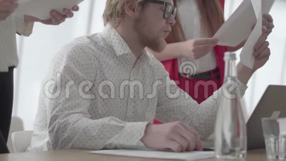 一位戴眼镜的成功金发男子坐在一间光线舒适的办公室里桌上挂着上网本视频的预览图