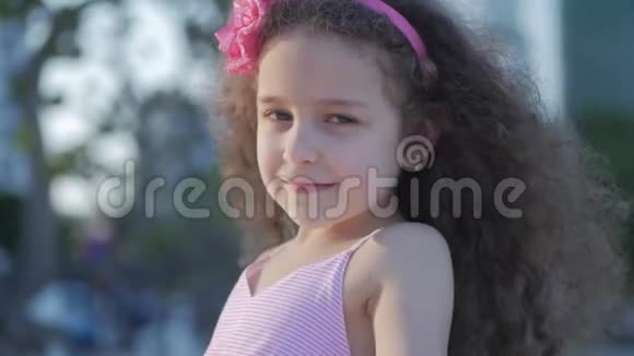肖像可爱的小白种人女性穿着粉红色衣服的儿童户外头上戴着粉红色的花看着视频的预览图