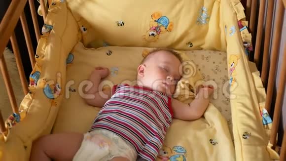 靠近一个小男孩睡觉婴儿躺在婴儿床上视频的预览图