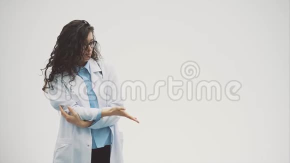 漂亮的年轻黑发医生穿着灰色背景的医疗服在这期间她身上有一个音筒视频的预览图