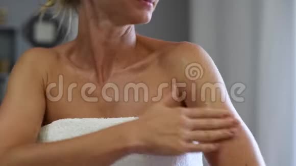 沐浴后裹着毛巾的美女正在晒黑的皮肤上涂抹沐浴露视频的预览图