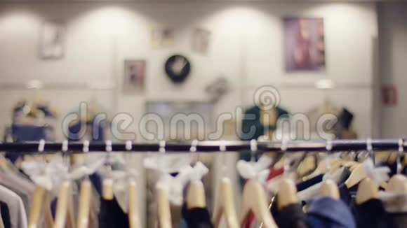 在一家服装店里一个漂亮的年轻女人走在衣服架边视频的预览图