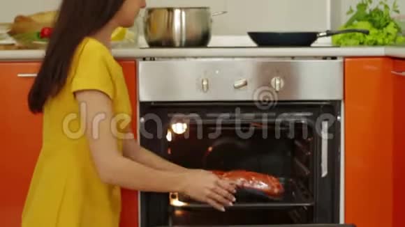 年轻女子在烤箱里准备肉视频的预览图
