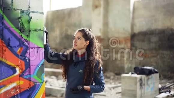 废弃建筑墙上涂鸦艺术家用气溶胶喷漆的慢动作可爱的女孩视频的预览图