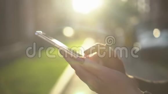 合上女人手拿白色电话智能手机金色阳光背景阳光阳光上网视频的预览图