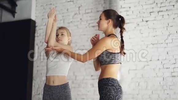 专业的瑜伽教练正在教新学生做手臂扭转同时进行个人健康练习视频的预览图