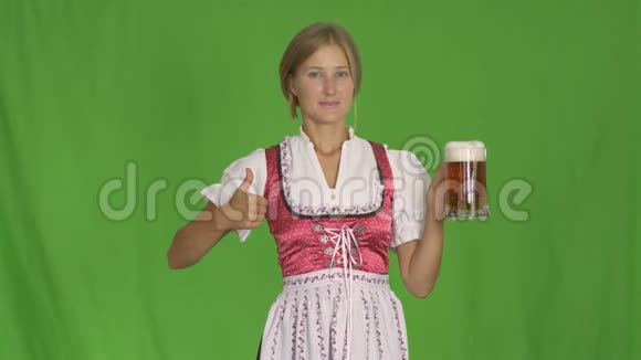 女孩把一杯啤酒放在一个孤立的绿色背景上巴伐利亚啤酒节庆祝活动视频的预览图