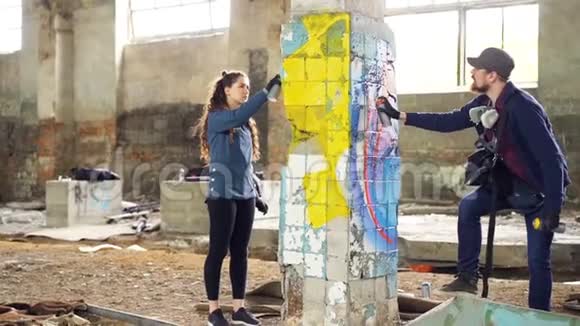 慢动作的创意涂鸦画家合作伙伴用明亮的气溶胶用美丽的图像装饰废弃的房子视频的预览图