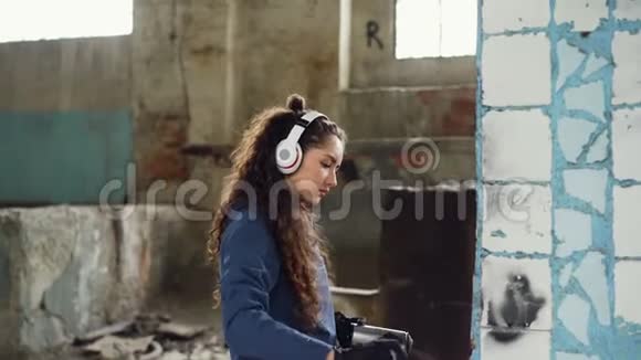 集中妇女正在废弃工业建筑内用喷漆涂鸦装饰旧的破损柱子视频的预览图