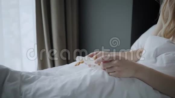 准备睡觉的女人戴上睡觉面具眼睛上的眼罩早上在酒店房间白色枕头和视频的预览图