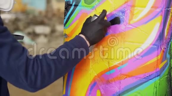 在废弃的旧柱子上用手握喷漆和涂鸦的皮革手套中男性手的特写镜头视频的预览图