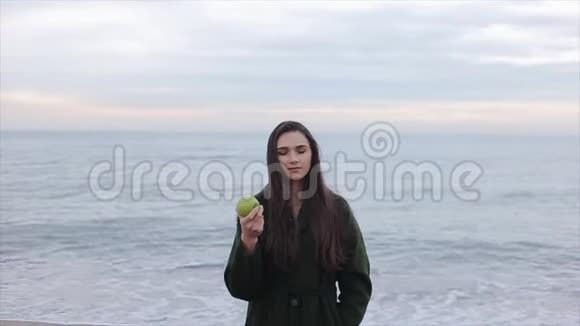一幅美丽快乐的女孩在寒冷的天气里抱着吃苹果的画像视频的预览图