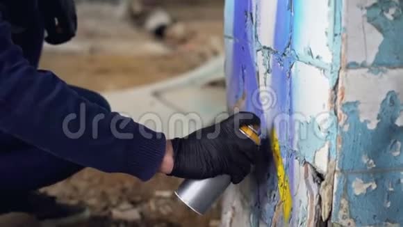 近距离拍摄男性手戴防护手套手持气溶胶涂料并在废弃的柱子上涂鸦视频的预览图