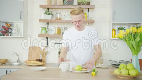 快乐的金发男人正在厨房吃早餐时喝咖啡视频的预览图