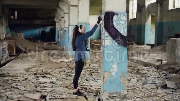 城市艺术家正在废弃的仓库里用气溶胶油漆用抽象的图像装饰柱子女孩穿着休闲装视频的预览图