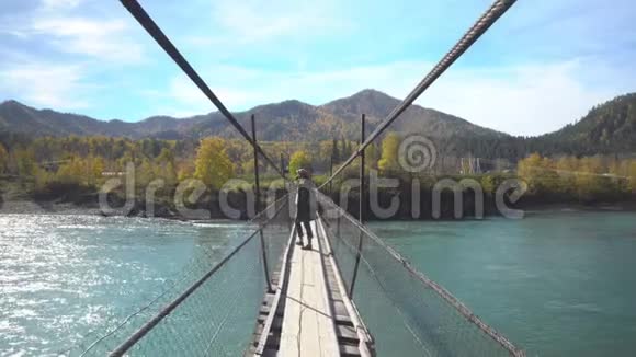 穿山河的吊桥上的女旅行者河的景色视频的预览图