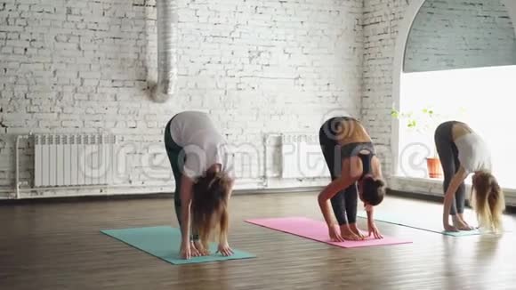 三位年轻女性正在练习瑜伽在光线下的瑜伽垫上做太阳敬礼的元素视频的预览图