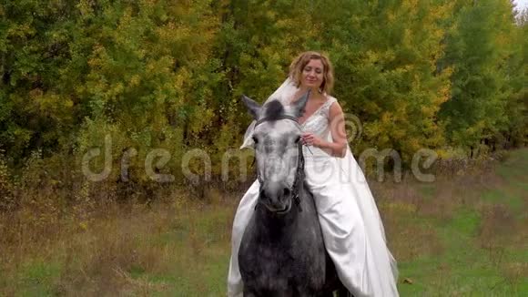 穿白色婚纱的女人在抚摸马关门视频的预览图