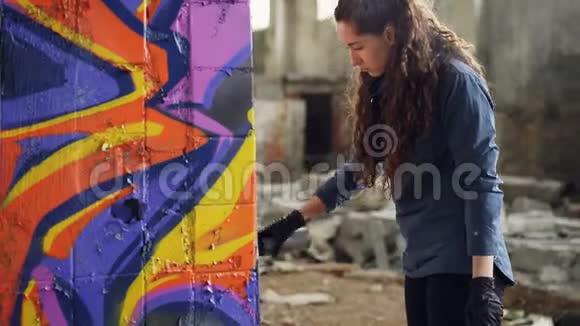 严肃的年轻女子涂鸦艺术家正在旧仓库的柱子上使用喷漆废弃的肮脏建筑视频的预览图