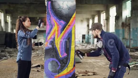 城市画家们集中精力在废弃的空房子里的柱子上涂鸦视频的预览图