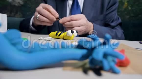 特写男在桌上为玩具蜜蜂做塑料条纹视频的预览图