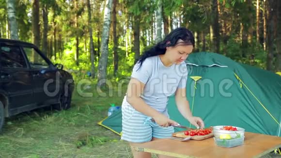 一个年轻的女人正在野餐时用刀切樱桃番茄做沙拉视频的预览图