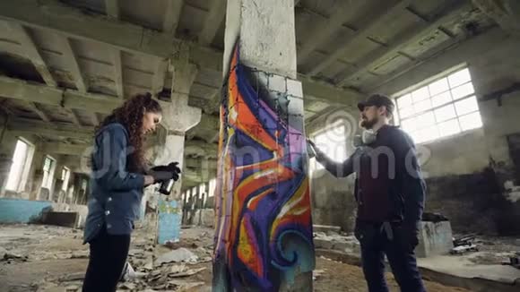 用气雾漆装饰废弃工业建筑的涂鸦画家的低角度镜头视频的预览图