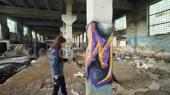 青年涂鸦艺术家们用气雾漆用现代涂鸦装饰废弃的工业建筑视频的预览图