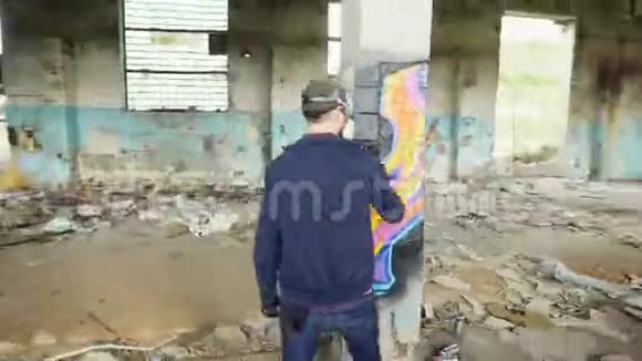 涂鸦艺术家们正在用气溶胶颜料用现代涂鸦装饰废弃的工业建筑视频的预览图