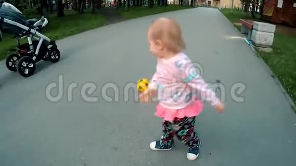 金发小女孩在公园里追逐着球阳光明媚的一天快速的慢动作视频的预览图