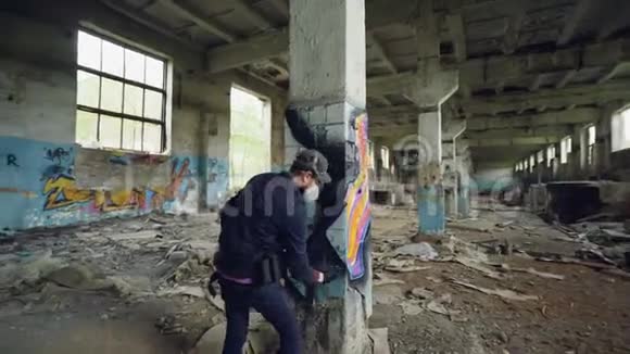 成人涂鸦艺术家用防护面罩和手套在损坏的空柱上作画视频的预览图