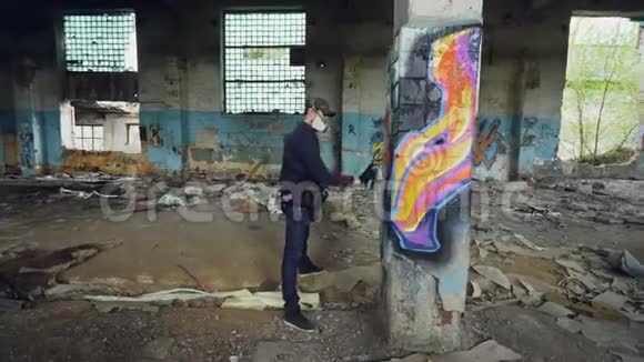 男性涂鸦艺术家正在用抽象的图片装饰空工业建筑内的旧损坏的柱子现代视频的预览图