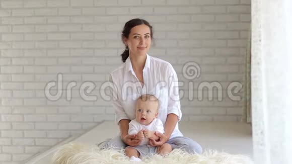 妈妈把孩子抱在怀里坐在地上铺着一条毛绒毯视频的预览图