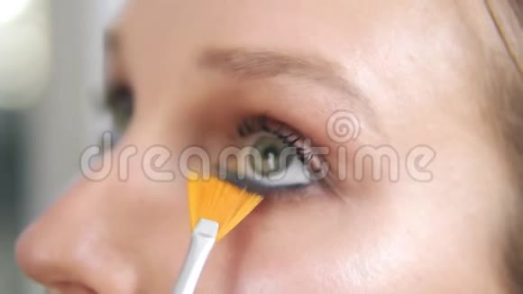 化妆师用专业的流苏画下眼睑的睫毛有蓝色眼线的女孩模特视频的预览图