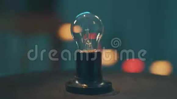 摄像机围绕放置在暗圆桌上的一盏灯泡动态旋转视频的预览图