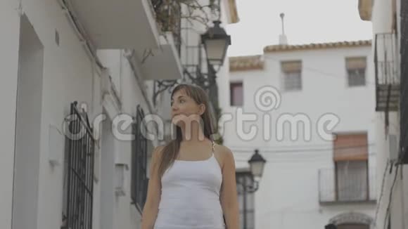 年轻迷人的女游客漫步在欧洲的一条街上白色的墙屋背景视频的预览图