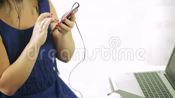 一个穿着蓝色裙子的年轻女子正在听她手机里的音乐特写镜头视频的预览图