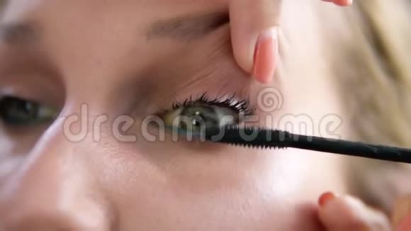 化妆师抬起模特的眼睑用睫毛膏沾上睫毛黑色近景视频的预览图