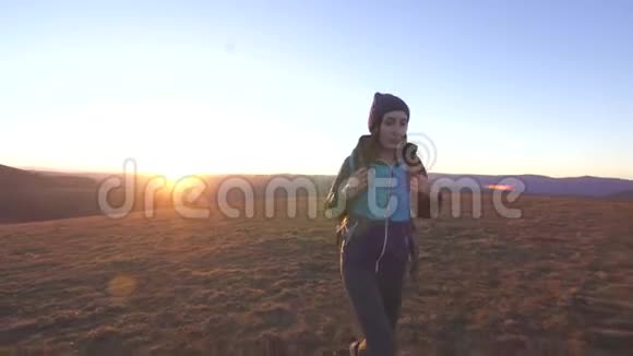 日落时分背着背包在山上漫步的女游客视频的预览图